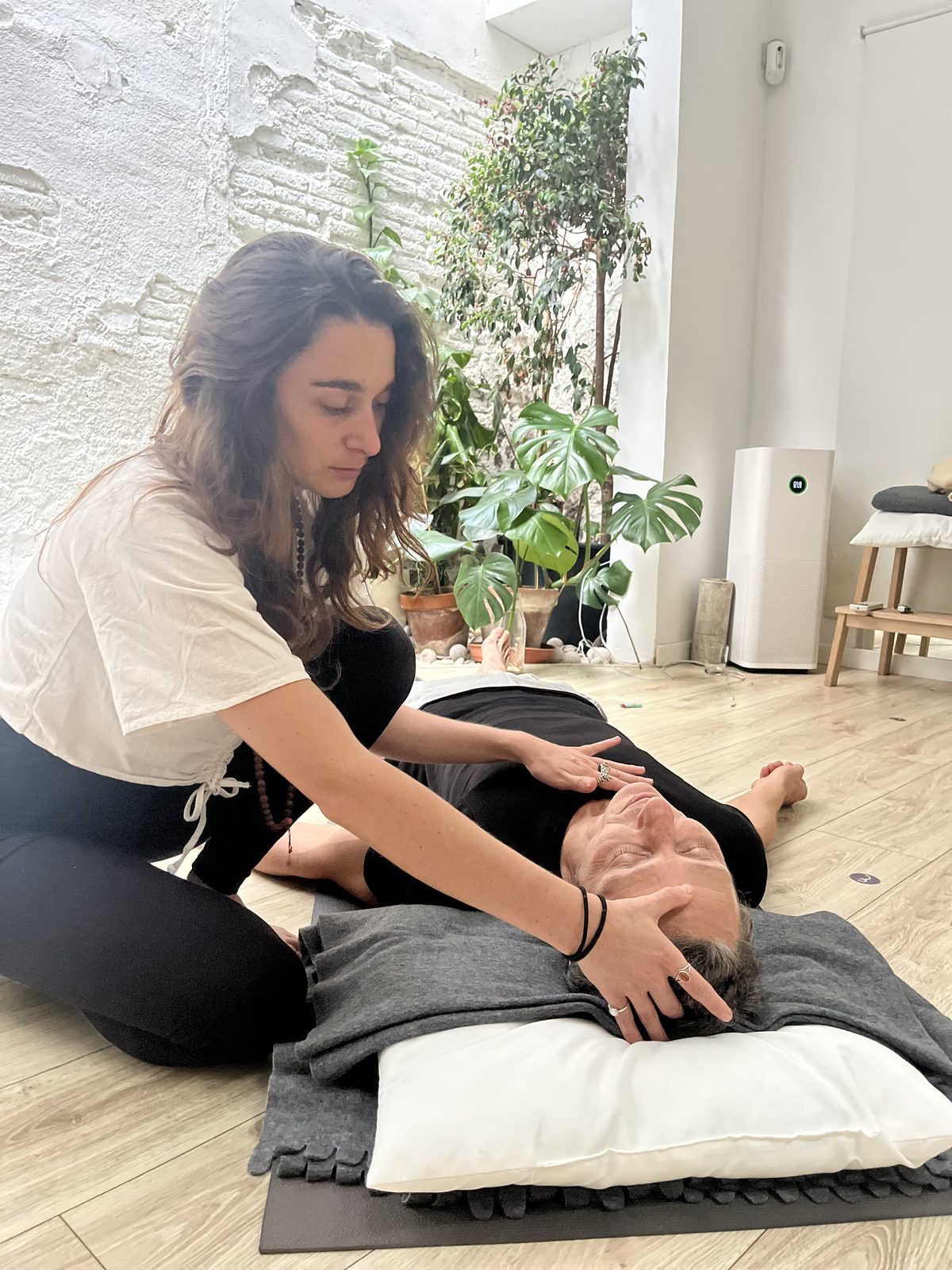 A facilitator resting her hands on a participant lying down during a Dreamwave session